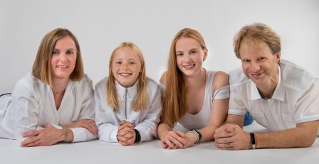 familienfoto auf weißem studiohintergrund sie liegen am bauch gestützt auf ihre unterarme und lachen in die kamera