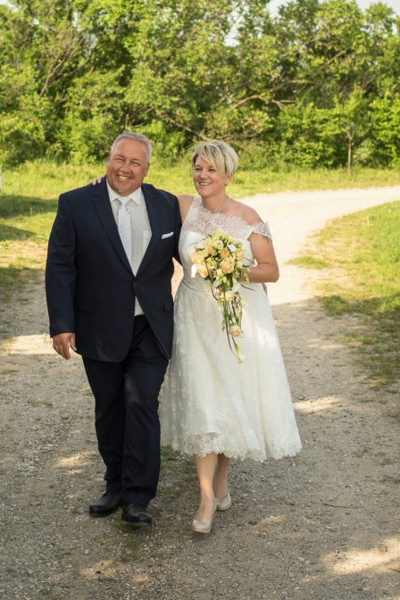 hochzeitsfoto das brautpaar läuft am feldweg auf die kamera zu und lacht